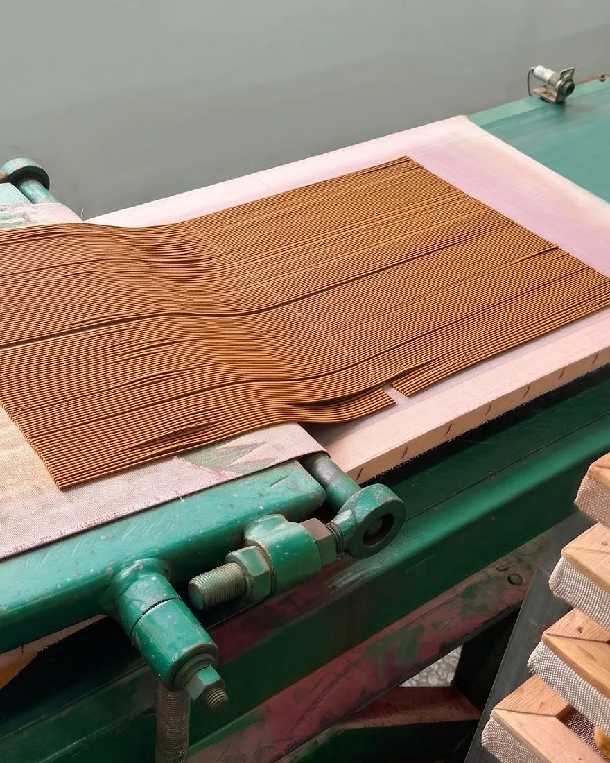 Freshly formed incense sticks laid out on the belt of a stick-making machine