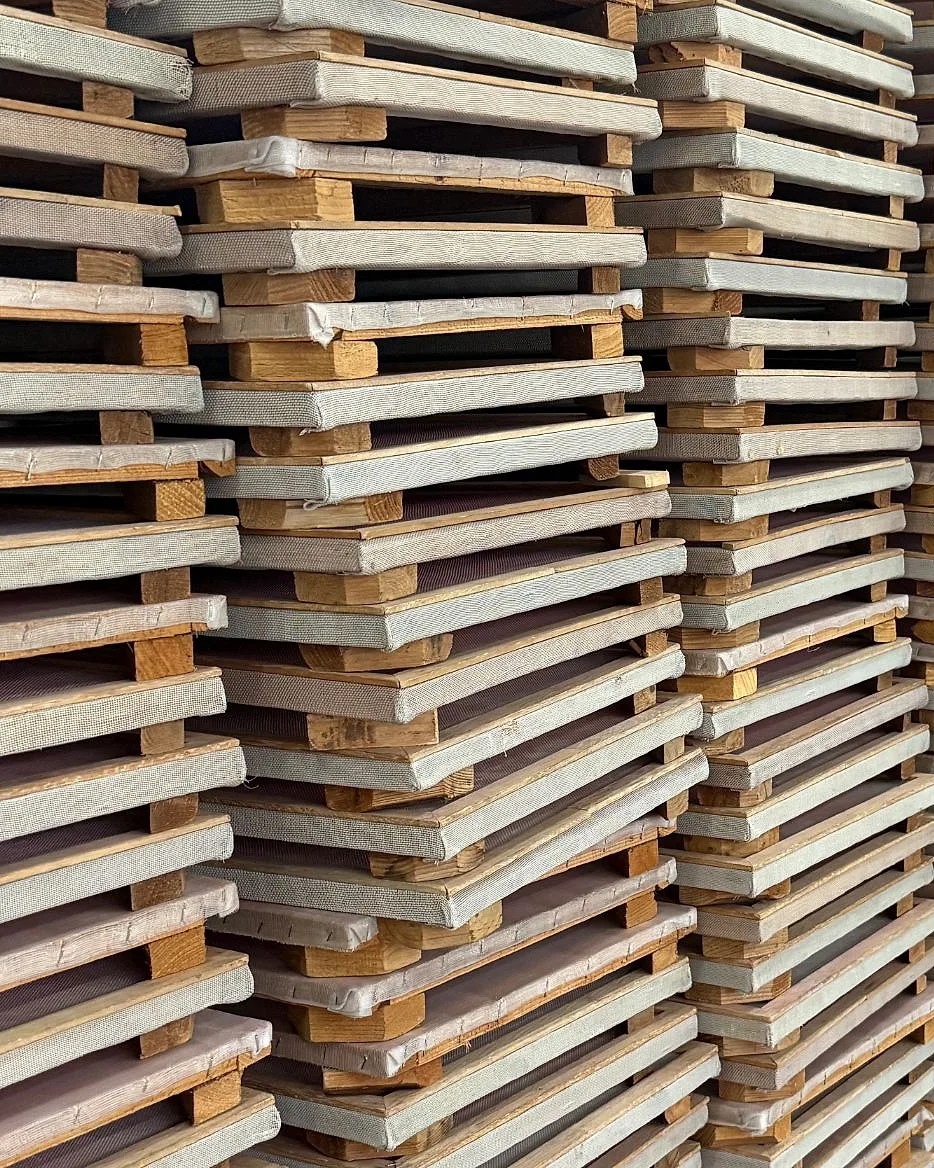 Stacks of wooden drying racks lined up along the production floor